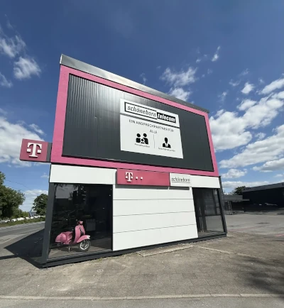 Modernes Telekom-Shop-Gebäude mit großem Werbeschild und pinkem Motorroller davor.